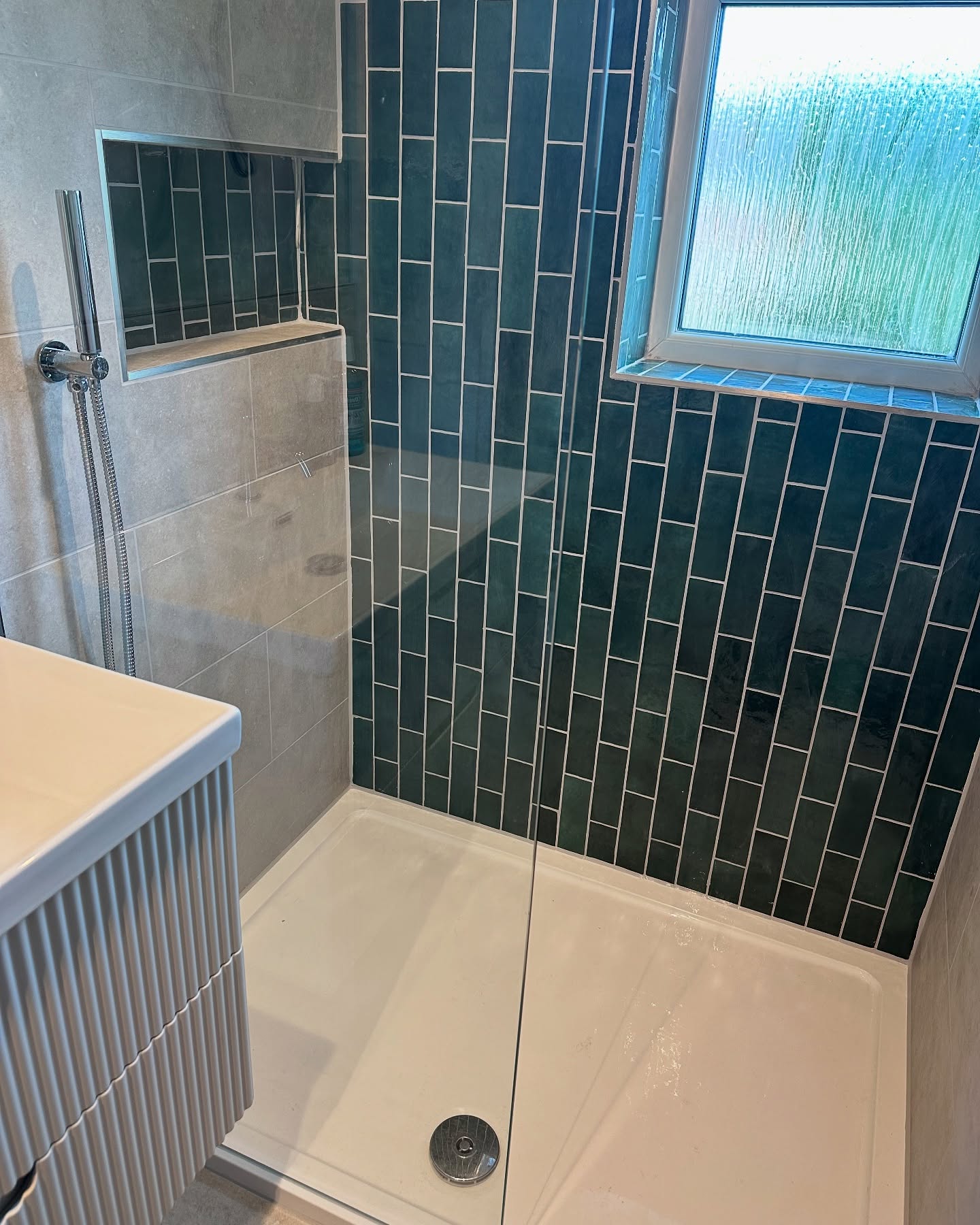 27. Tiled Mosaic Floor with Frosted Glass Partition and Corner Bench In a Compact Walk-in Shower