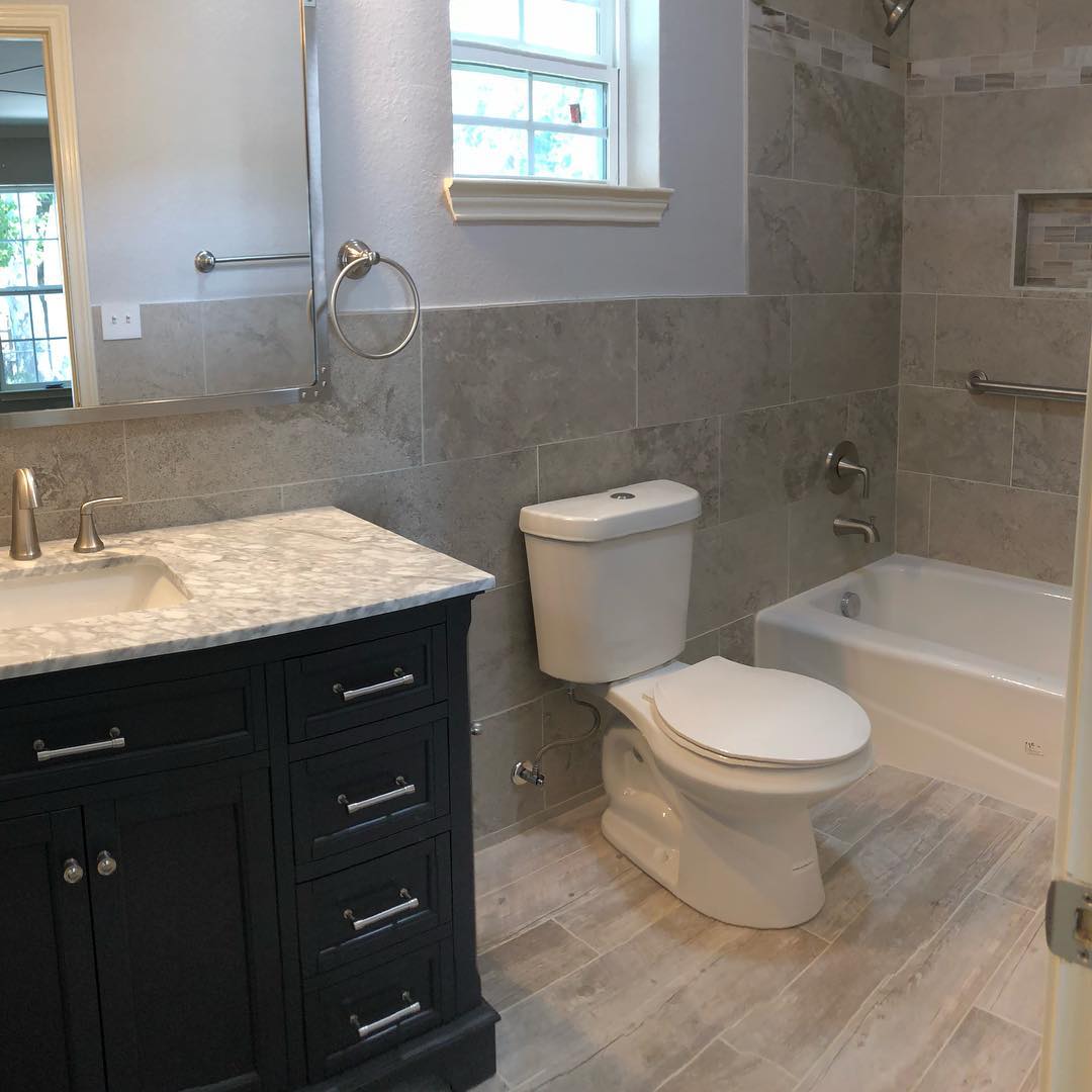 17. Sleek Black Tub with Integrated Chrome Fixtures and Pebbled Floor Contrast